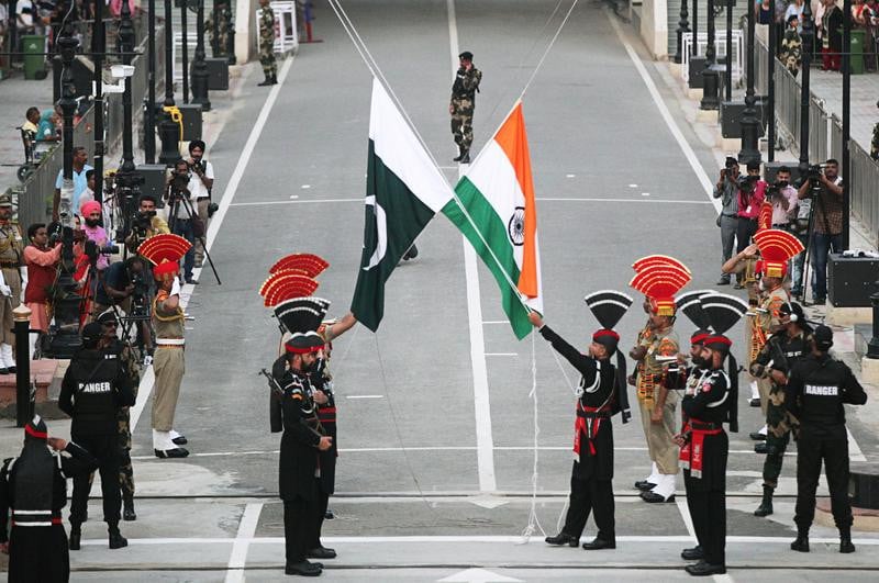 Pakistani Rangers (wearing black uniforms) and Indian Border Security Force (BSF) officers lower their national flags during parade on the Pakistan's 72nd Independence Day, at the Pakistan-India joint check-post at Wagah border, near Lahore. PHOTO: REUTERS/FILE